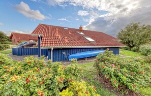A house with a red-tiled roof, a blue garage, and a swimming pool. - Nice home in Otterndorf with sauna (Otterndorf)