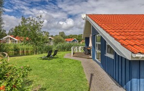 A residential property with a red-tiled roof, a blue exterior, and a grassy yard with two lounge chairs. - Nice home in Otterndorf with sauna (Otterndorf)