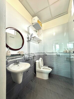 A modern bathroom with a large mirror, two sinks, a toilet, and a shower. - NESTA HOTEL  (Hoa Lu)