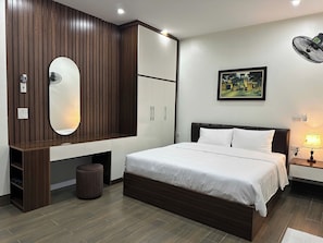 A bedroom with a bed, wardrobe, mirror, and a painting on the wall. - NESTA HOTEL  (Hoa Lu)