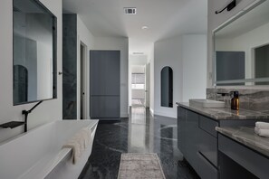 Une salle de bain moderne avec une baignoire, un meuble-lavabo et de grands miroirs.