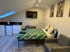 A compact room with a bed, a sofa, a small kitchenette, and a TV mounted on the wall. - Apartment Sleeps 3 near High Street (Thornton Heath)