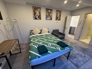 A bedroom with a bed, a chair, a table, and a shower area. - Apartment Sleeps 3 near High Street (Thornton Heath)