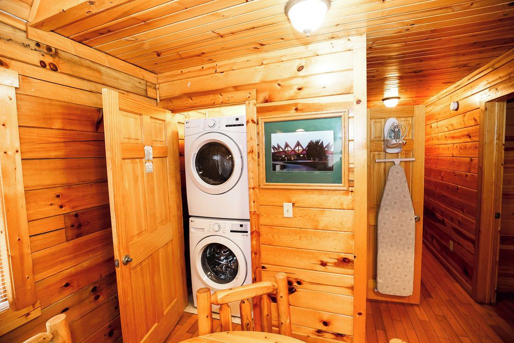 En stuga med träinredning, innehållande en tvättmaskin, en stol och en handduksställning.
