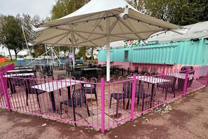 An outdoor dining area with tables and chairs, a tent providing shade, and a fenced enclosure. - Cabin Sleeps 6 with Dishwasher (Skegness)