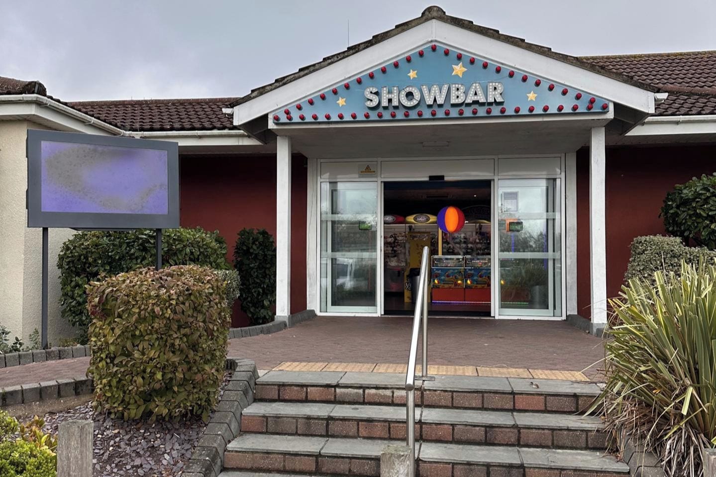 Un SHOWBAR amb façana vermella, tendal blau i rètol.