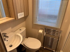 Ein kleines Badezimmer mit Toilette, Waschbecken und Handtuchhalter.