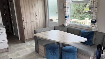 A compact kitchen with a dining area, including a table and a bench.
