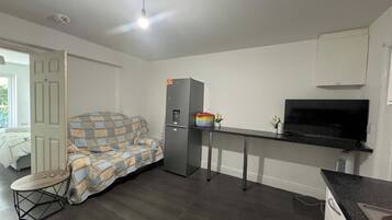 Ett kompakt bostadsutrymme med ett litet kök, en soffa, ett litet bord och en tv.