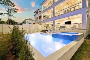 Un edificio residencial de varios pisos con piscina, mobiliario exterior y un patio cubierto.