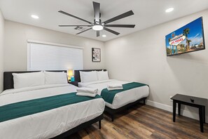 A hotel room with two beds, a ceiling fan, a painting, and a small table. - Pool & Spa • Game Room • King Beds • 20 Guests Max (Las Vegas)