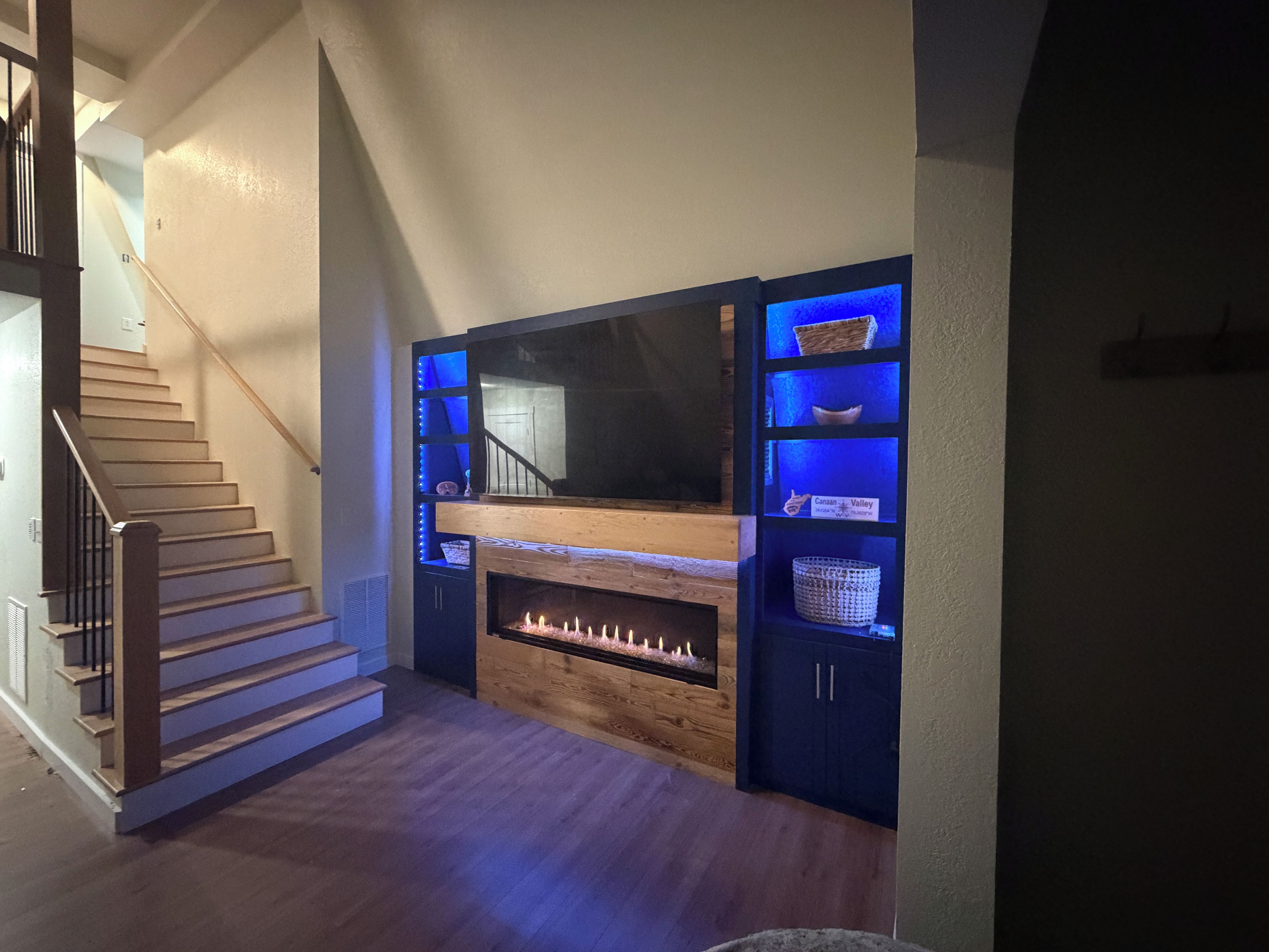 Un escalier menant à un palier agrémenté d’une cheminée et d’étagères intégrées où sont exposés des objets décoratifs.