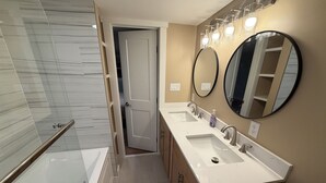 Ein modernes Badezimmer mit Duschkabine aus Glas, begehbarer Dusche, doppelter Waschtischablage und zwei wandmontierten Spiegeln.