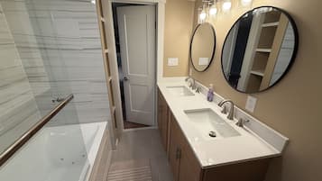 A modern bathroom with a glass shower enclosure, a walk-in shower, a double sink vanity, and two wall-mounted mirrors.