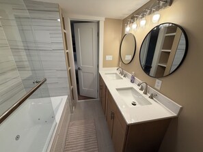 Une salle de bain moderne dotée d’une cabine de douche en verre, d’une douche à l’italienne, d’un meuble-lavabo à deux vasques et de deux miroirs fixés au mur.