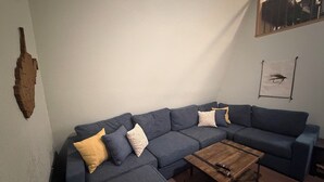 Ein Wohnzimmer mit einem Ecksofa, einem Couchtisch und einem Wandbild.