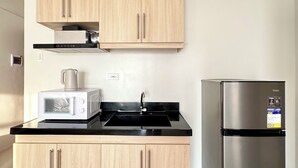 A modern kitchen with light wood cabinets, a stainless steel refrigerator, and a built-in microwave. - Royal Oceancrest Panglao 1 (Dauis)