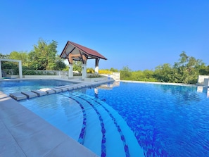 Una piscina azul cristalina con un pabellón y escalones que bajan al agua.
