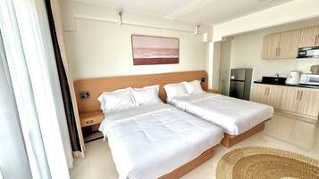 A hotel room with a double bed, a small kitchenette, and a bathroom.