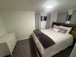 A bedroom with a bed, a dresser, a window with curtains, and a ceiling light. - Bennett Burrow! Newly Renovated home 8 Blocks from Spokane Arena/Riverfront Park (Spokane)