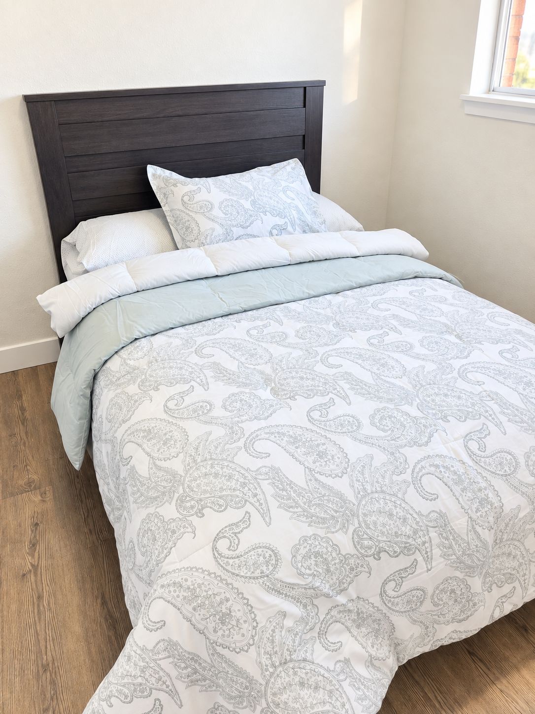 A bed with a dark headboard, multiple pillows, and a patterned bedspread.