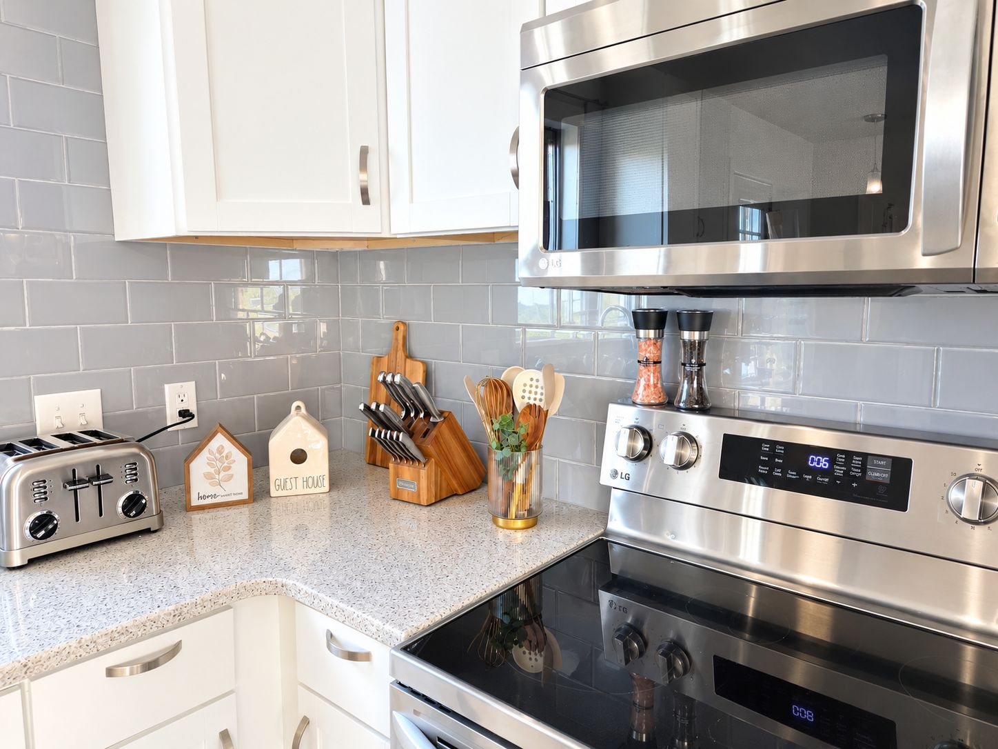 A kitchen with a toaster, microwave, and oven. There are wooden utensils and a spice rack on the counter.