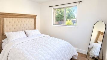 Un dormitorio con una cama grande, una ventana con vistas, una lámpara de techo y un espejo.