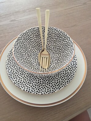 A table setting with a white plate, a black and white patterned bowl, and a fork.
