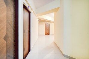 A corridor with a wooden door on the left and a plain door on the right, leading to a room.