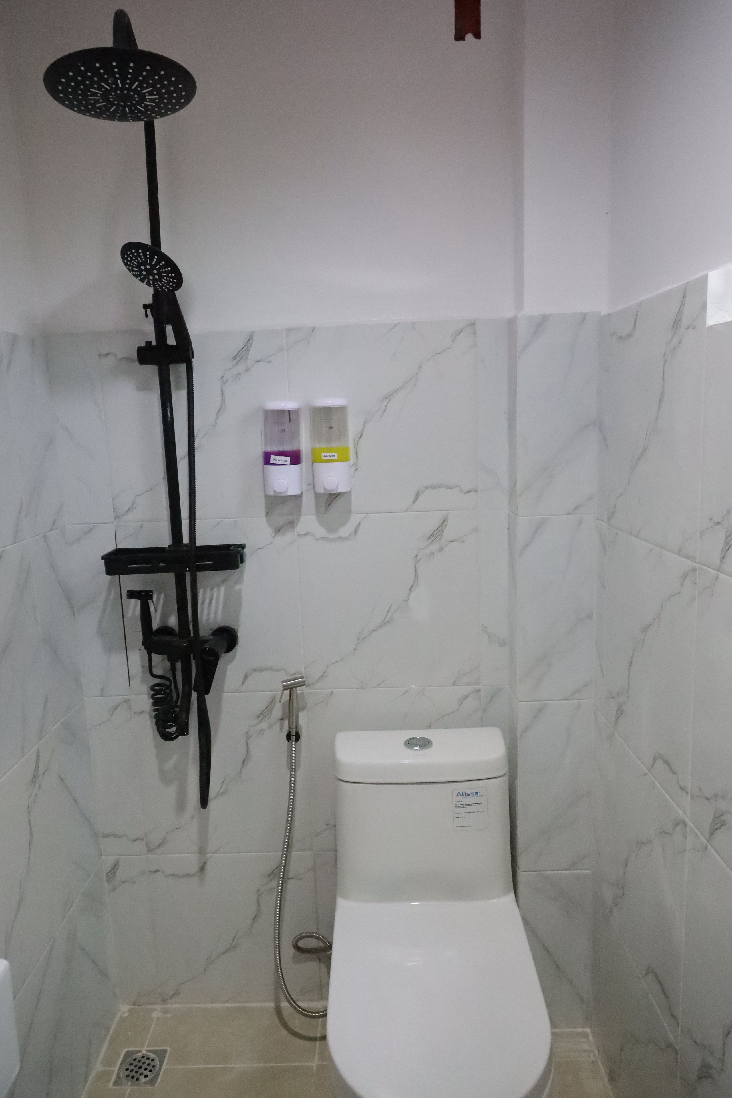 A bathroom with a shower, toilet, and hand soap dispensers.