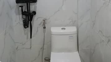 A bathroom with a shower, toilet, and hand soap dispensers.