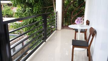 A balcony with a table and chairs, surrounded by greenery.