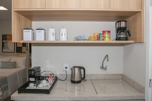 A kitchenette with a coffee maker, a kettle, and storage containers on the countertop. - Premium studio near Faria Lima (São Paulo)