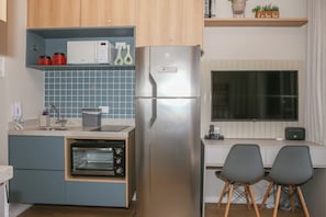 A compact kitchen with a built-in oven, a refrigerator, and a window above the sink. - Premium studio near Faria Lima (São Paulo)
