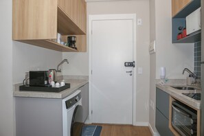 A compact kitchen with a coffee maker, a toaster, a sink, and a built-in oven. - Premium studio near Faria Lima (São Paulo)
