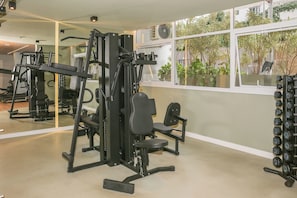 A gym with exercise equipment, a mirror, and a view of greenery outside. - Premium studio near Faria Lima (São Paulo)