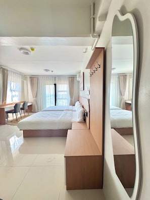Habitación de hotel con una cama grande, un escritorio, sillas, un espejo y vistas al exterior.