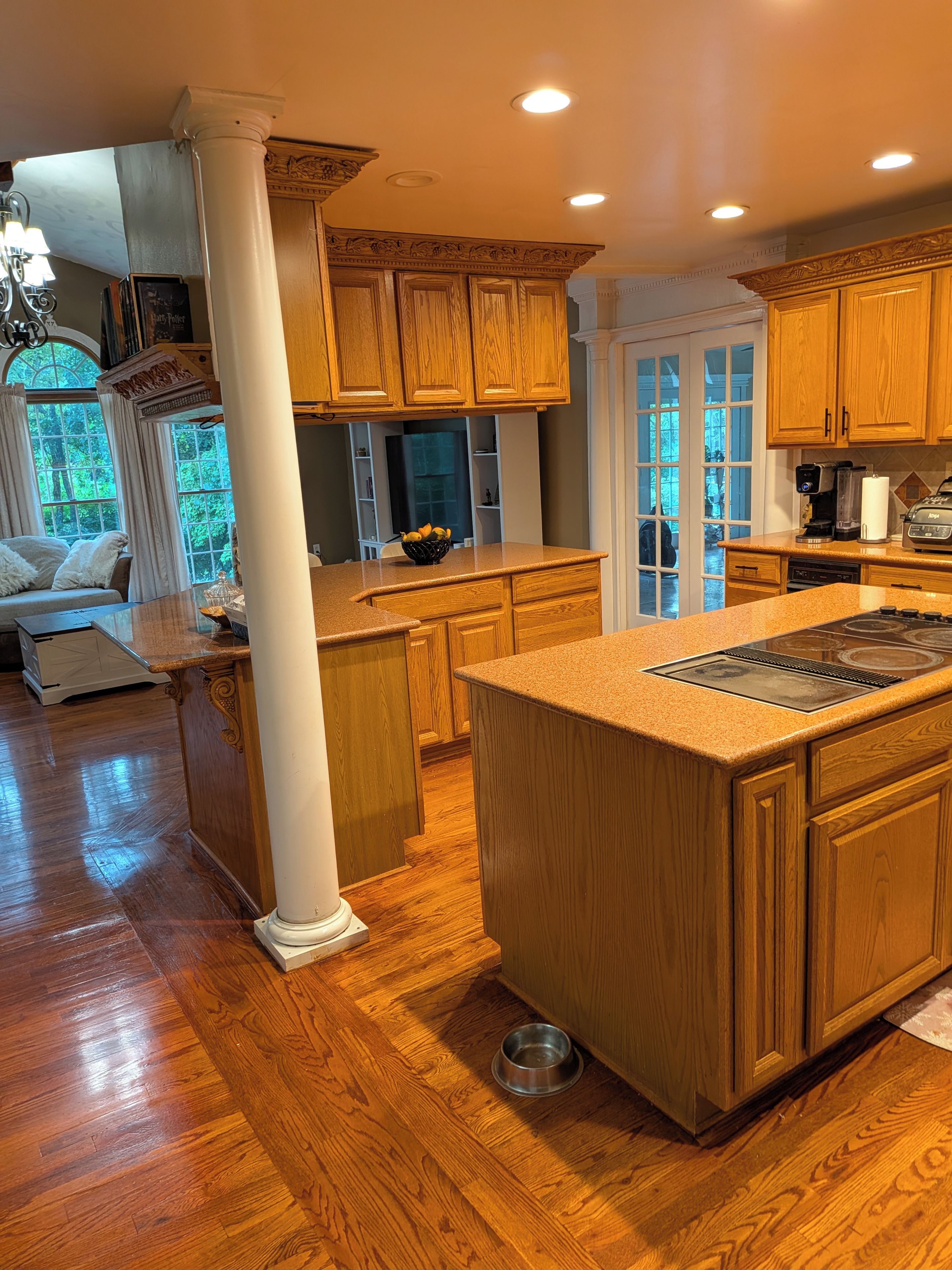 A kitchen with wooden cabinets, a large island, and a view of the outdoors.