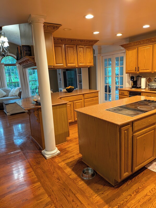 A kitchen with wooden cabinets, a large island, and a view of the outdoors.