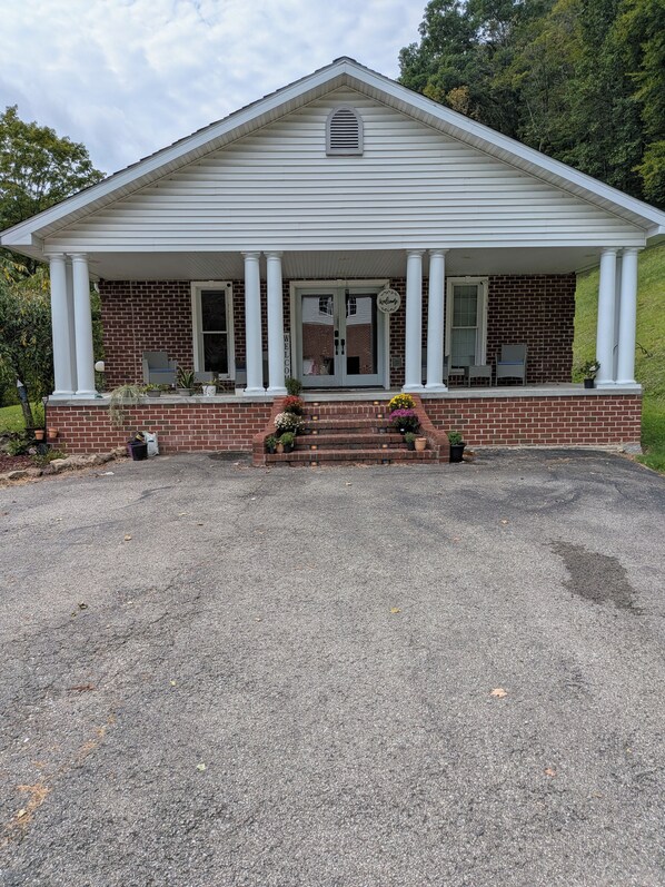A two-story building with a brick facade and a white porch supported by columns. - Spacious 4-bedroom house in Delbarton WV with AC (Delbarton)