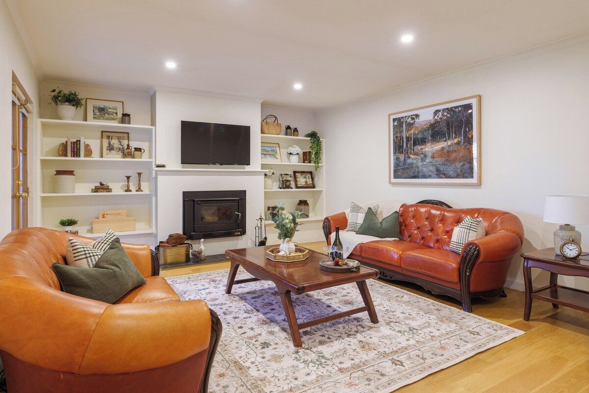 A living room with a fireplace, leather sofas, a coffee table, and a large painting on the wall.