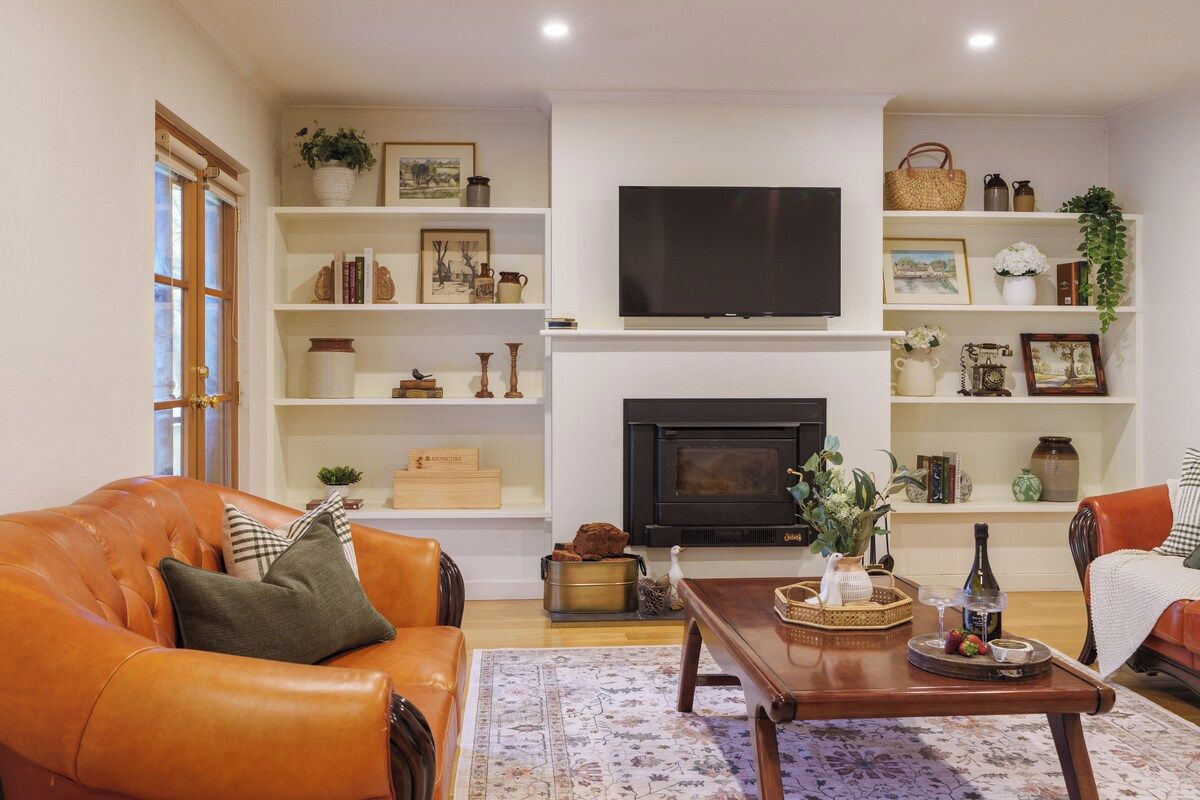 A living room with a fireplace, a television, and a coffee table with decorative items.