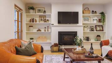 A living room with a fireplace, a television, and a coffee table with decorative items.