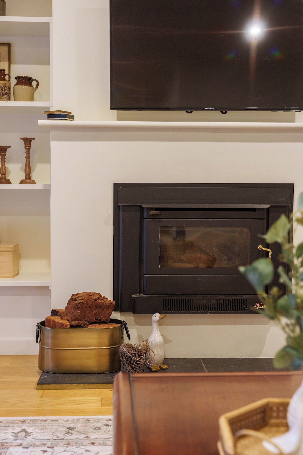 A living room with a fireplace, a television mounted above it, and a wooden coffee table.