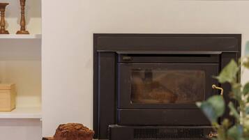 A living room with a fireplace, a television mounted above it, and a wooden coffee table.