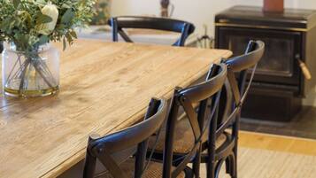 A dining area with a wooden table, black chairs, a vase with flowers, and a painting on the wall.