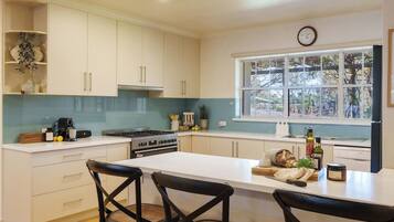 A modern kitchen with white cabinets, a central island, and a window with a view of trees.