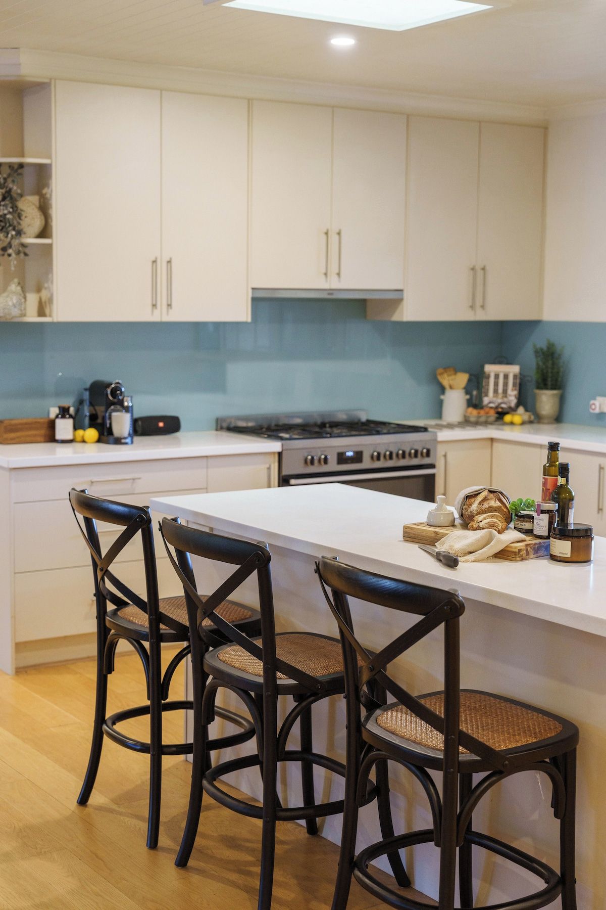 A modern kitchen with white cabinets, a central island with chairs, and a stove.