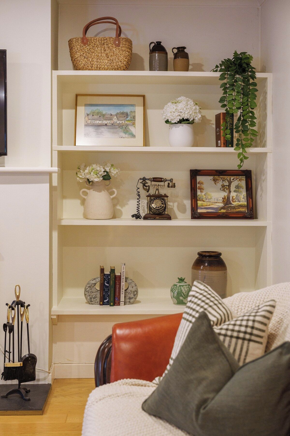 A living room with a sofa, a coffee table, and shelves with decorative items and books.