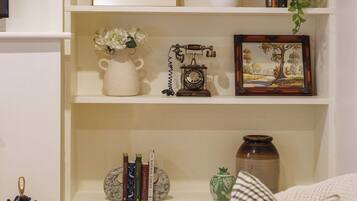 A living room with a sofa, a coffee table, and shelves with decorative items and books.
